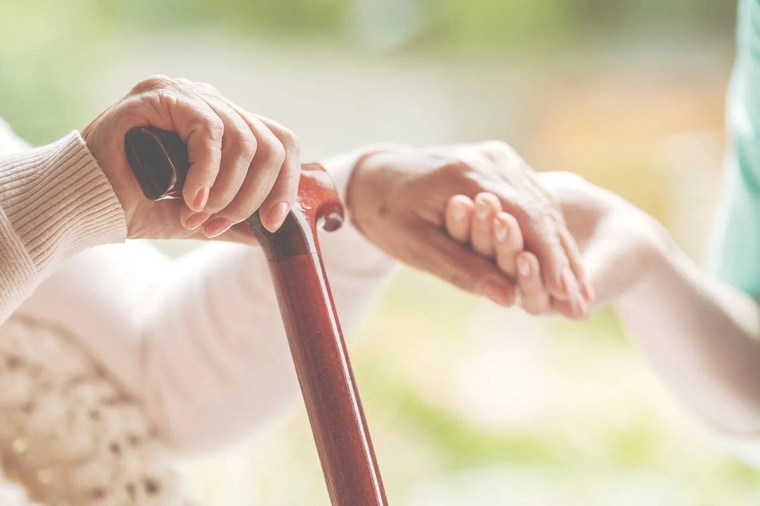 Nahaufnahme der älteren Dame, die Gehstock in einer Hand hält und die Hand der Krankenschwester in der anderen